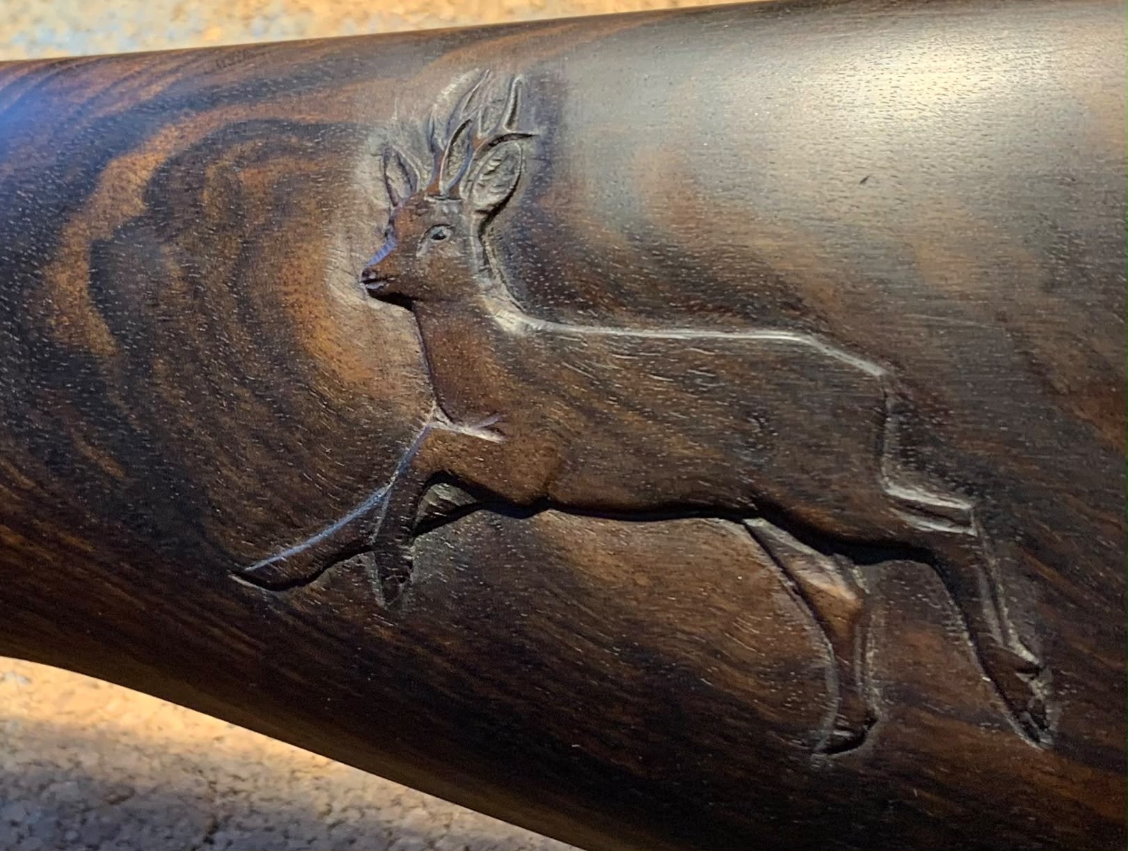 Détail d’une crosse en noyer sculptée en bas-relief : chevreuil en course